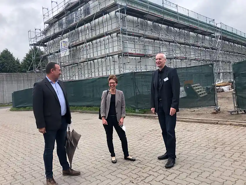 Marko Rothaar (links), zuständig für Liegenschaften im Justizressort und der Leiter der JVA, Hans-Jürgen Erdtmann (rechts) erläuterten Senatorin Claudia Schilling den Baufortschritt des neuen Container-Hafthauses im Hintergrund. Foto: Justizressort