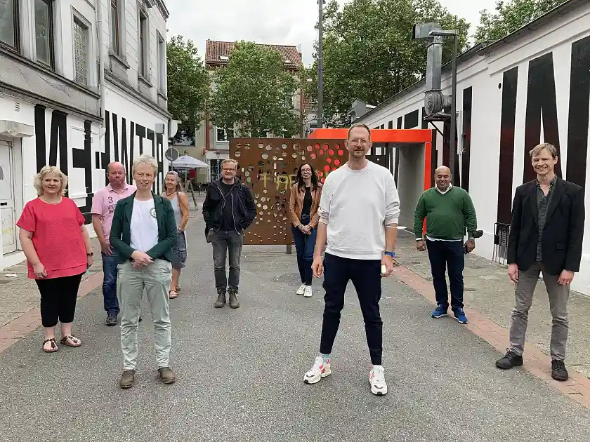 Der Eingangsbereich der Helenenstraße mit Blickrichtung Steintor, der von dem Künstler Sebastian Dannenberg (3.v.re.) neu interpretiert wurde. Kulturstaatsrätin Carmen Emigholz (4.v.re.) und Ortsamtsleiterin Hellena Harttung (3. v. l.) nach der offiziellen Übergabe, zusammen mit den weiteren Beteiligten des Wettbewerbs Ingmar Lähnemann (1.v.re.) von der Städtischen Galerie Bremen und Steffen Eilers (5.v.li.), Beiratsmitglied Mitte/Östliche Vorstadt. Ebenfalls dabei Bettina Marten-Jähnke (1.v.li.) und Herr Aktas (2.v.re.), die Hausbesitzer der beiden bearbeiteten Wände, sowie Sagitta Paul (4.v.li.) als Vertreterin vom Verein Nitribitt und Sven Schleider (2.v.li.) vom Malerfachbetrieb Schleider. Foto: Kulturressort