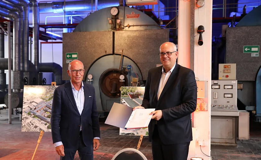 Vor alten Maschinen die Unterschrift für die Zukunft im Tabakquartier: Bürgermeister Dr. Andreas Bovenschulte (rechts) und der geschäftsführende Gesellschafter der Justus Grosse Real Estate GmbH, Joachim Linnemann. Foto: Justus Grosse Real Estate GmbH