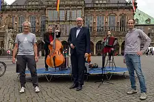 Eine neue mobile Lastenradbühne für Bremen – v.l. BIKE IT!-Projektleiter Jens Joos-Krüger (WFB), Bürgermeister und Kultursenator Dr. Andreas Bovenschulte und BIKE IT!-Koordinator Peter Sämann (WFB) präsentieren das flexible Lastenrad auf dem Bremer Marktplatz. Foto: WFB/Michael Bahlo