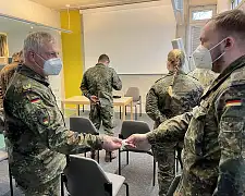 General Andreas Henne (links) überreicht den Soldatinnen und Soldaten im Gesundheitsamt einen Coin des Kommandos Territoriale Aufgaben. Inschrift: "Dank und Anerkennung - Hilfeleistung Corona". Foto: Bundeswehr/Krey 
