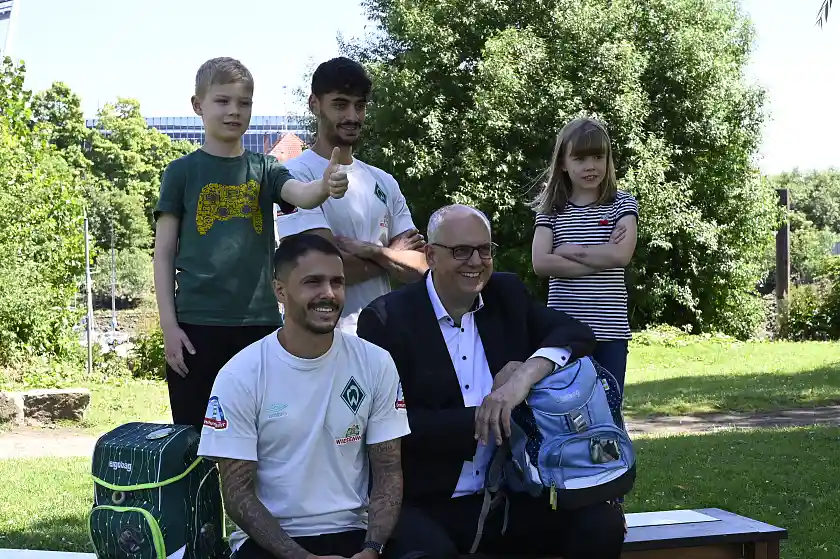 Bürgermeister Andreas Bovenschulte sitzt für die Aktion Wer selber geht, der ist schon groß vor der Kamera. Personen (v.l.n.r.): Fiete, Schüler; Leonardo Bittencourt und Eren Dinkci, Werder Bremen; Bürgermeister Andreas Bovenschulte; Jule, Schülerin. Quelle: Senatspressestelle