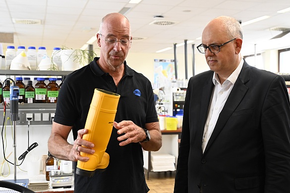 Laborleiter Dr. Holger Klyszcz-Nasko (links) erläutert Bürgermeister Bovenschulte anhand eines Gummistiefels, welche Rolle Trennmittel von ACMOS in der Industrie spielen. Foto: Senatspressestelle