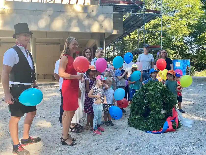 Kinder, Handwerker und Beschäftigte der Kita Charlotte Niehaus freuen sich mit Kinder- und Bildungssenatorin Sascha Karolin Aulepp (2. von links) und die AWO-Präsidentin Sarah Ryglewski (3. von links) über den Richtkranz für das neue Kinder- und Familienzentrum. Foto: Bildungsressort
