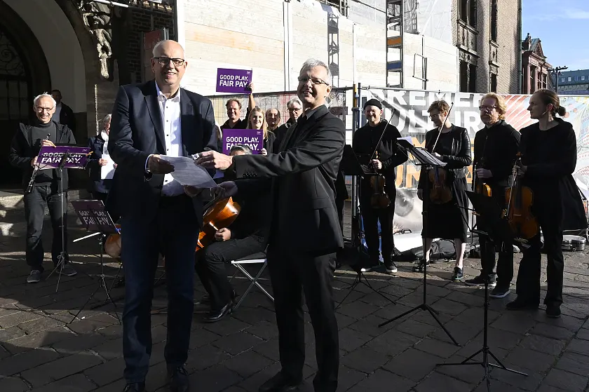 Rafael Wewer, Violinist bei den Bremer Philharmoniker, überreicht Bürgermeister und Kultursenator Andreas Bovenschulte den offenen Brief der Deutschen Orchestervereinigung. Foto: Senatspressestelle