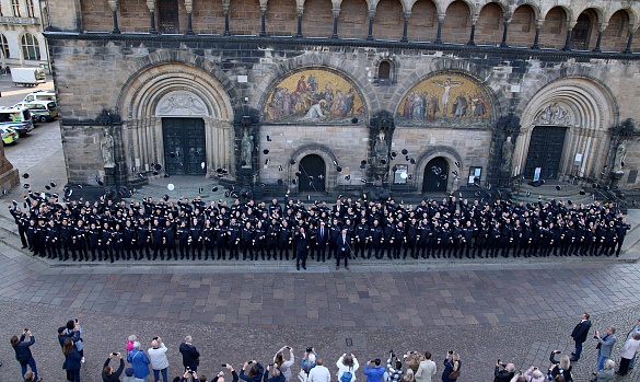 Die Mützen fliegen: Nach der Zeugnisübergabe versammelten sich die neuen Polizeikommissarinnen und –kommissare auf den Stufen des Doms. Foto: Innenressort