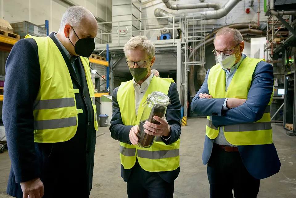 Bürgermeister Andres Bovenschulte (links) und Nils Schnorrenberger (Geschäftsführer der Bremerhavener Wirtschaftsförderungsgesellschaft BIS, rechts) informieren sich über die Aktivmasse, einem hochwertigen Outputprodukt bei Redux-Geschäftsführer Martin Reichstein (Mitte). Foto: Redux/Schimanke