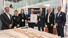 Auf dem Bremer Gemeinschaftsstand auf der Expo Real 2022 überreichte Hermann Horster, Vizepräsident der Deutschen Gesellschaft für Nachhaltiges Bauen (DGNB) der Geschäftsleitung von Peper & Söhne, Christoph Peper, Malte Wilkens und Nico Grutzpalk, das DGNB-Vorzertifikat in Gold für das Spurwerk in Anwesenheit der Bremer Senatsbaudirektorin Prof. Dr. Iris Reuther. Foto: WFB/Jan Rathke