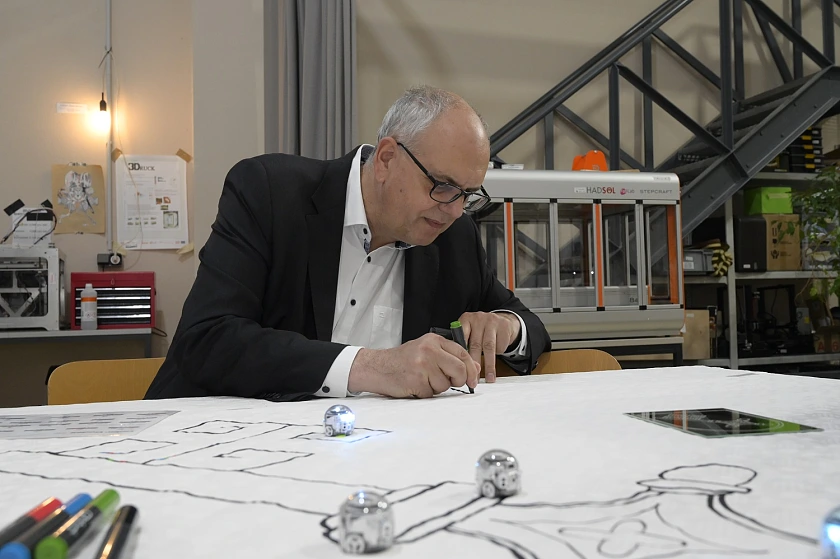 Mit verschiedenen Farben programmiert Bürgermeister Bovenschulte auf einem Stück Papier die Laufrichtung des Mini-Roboters Ozobot. Foto: Senatspressestelle