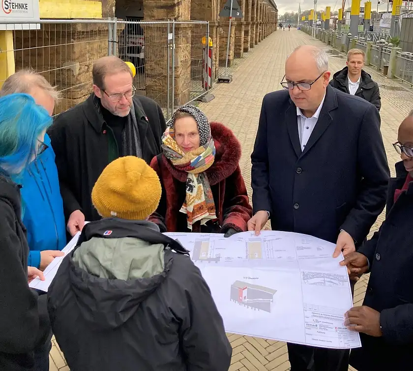 Evin Oettingshausen (vorne) erläutert den künstlerischen Entwurf für Bürgermeister Bovenschulte (2.v.r.) Elvira Noa (3.v.r.) und die Kulturdeputationsmitglieder Elombo Bolayela (1.v.r.), Claas Rohmeyer (3.v.l.) und Kai Wargalla (1.v.l.). Foto: Kulturressort