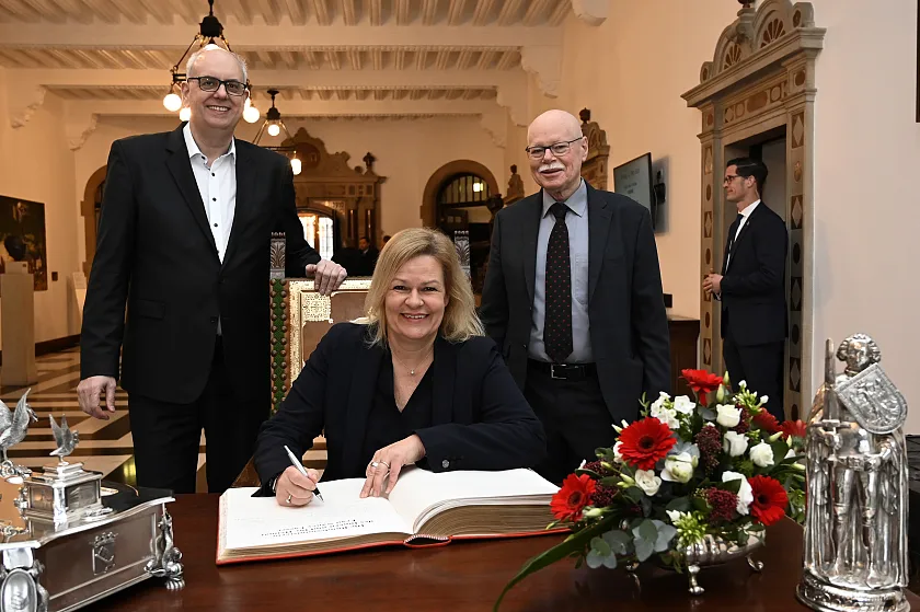 Bundesinnenministerin Nancy Faeser beim Eintrag in das Goldene Buch zusammen mit Bürgermeister Andreas Bovenschulte (links) und Innensenator Ulrich Mäurer. Foto: Senatspressestelle