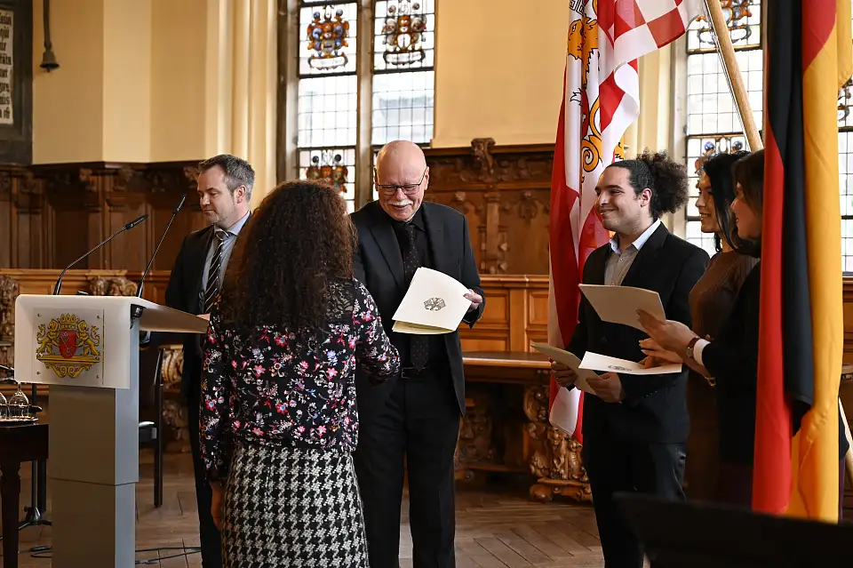 Innensenator Ulrich Mäurer überreicht den neu eingebürgerten Bremerinnen und Bremern ihre Urkunde. Foto: Senatspressestelle