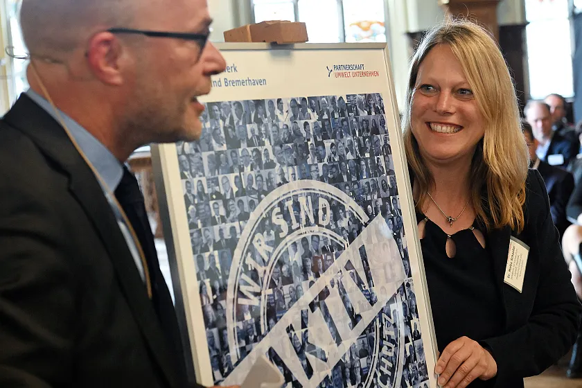 Martin Schulze, Leiter der Geschäftsstelle Umwelt Unternehmen, überreichte Dr. Maike Schaefer ein Jubiläumsposter zum 20-jährigen Bestehen der Umweltpartnerschaft. Foto: Umwelt Unternehmen, Fotograf Michael Bahlo