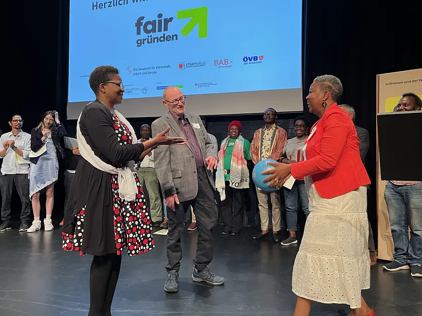 Jurymitglied Virginie Kamche wirft den Erstplazierten der Crowndfunding-Kampagne fair gründen, Ziporah Zebedayo-Thomas und Manfred Thomas ihren symbolischen Preis, einen Beachvolleyball aus Fairem Handel, zu. Der Gewinn ist mit 3.000 Euro dotiert. Foto: Senatspressestelle