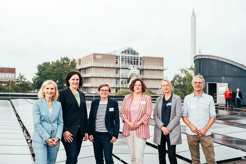 Ein gutes Beispiel für Nachhaltigkeit ist die Photovoltaik-Anlage auf dem Dach der Mensa der Universität Bremen. Von links: Prof. Dr. Jutta Günther (Rektorin Universität Bremen), Kathrin Moosdorf (Senatorin für Klima, Umwelt und Wissenschaft), Dr. Britta Lüder (Konrektorin für Forschung und Transfer Hochschule Bremen), Dr. Antje Stephan (Kanzlerin Hochschule für Künste), Prof. Dr. Rabea Diekmann (Konrektorin für Forschung, Transfer & Weiterbildung Hochschule Bremerhaven), Prof. Dr. Marko Rohlfs (Projektkoordinator BreGoS) wollen mehr solcher Projekte an den Hochschulen des Landes Bremen verwirklichen. Foto: Lukas Klose/Universität Bremen