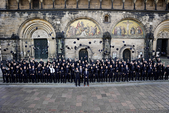 Die Mützen fliegen: Nach der Zeugnisübergabe versammelten sich die neuen Polizeikommissarinnen und –kommissare auf den Stufen des Doms. Foto: Innenressort