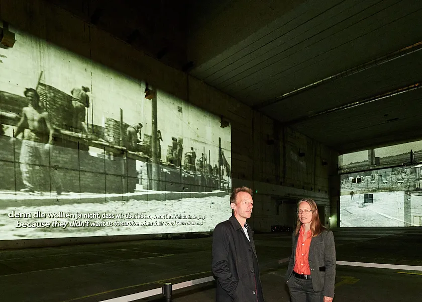 Senatorin Sascha Karolin Aulepp und der Leiter der Landeszentral für politische Bildung Bremen, Dr. Thomas Köcher, vor der neuen Projektions-Installation im Bunker Valentin. Foto: Bildungsressort, Michael Schnelle