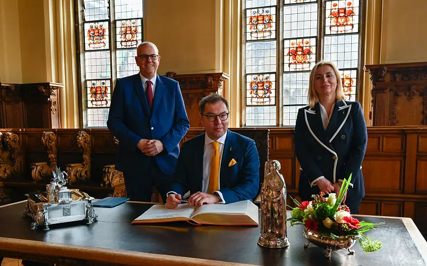 Eintrag in das Goldene Buch: Botschafter Oleksii Makeiev (sitzend), Bürgermeister Andreas Bovenschulte und Generalkonsulin Iryna Tybinka. Foto: Senatspressestelle