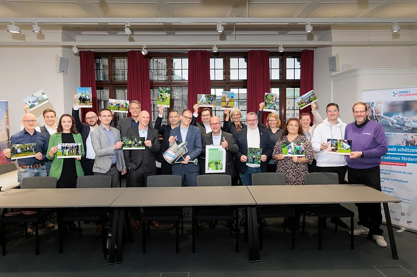 Vertreterinnen und Vertreter der teilnehmenden Unternehmen präsentieren mit Fotos die erfolgreiche Baumpflanzaktion der Umweltpartnerschaft im Bremer Rathaus. Foto: Umwelt Unternehmen, Jörg Sarbachv