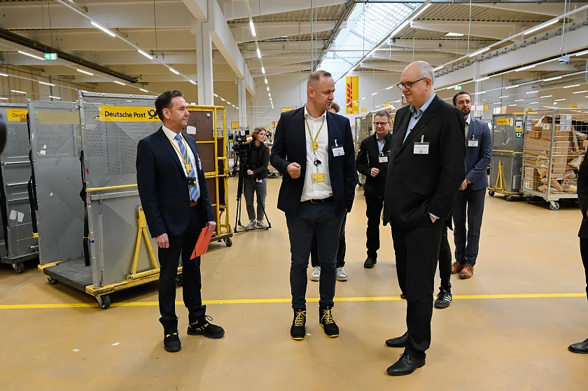 Bei einem anschließenden Rundgang erhielt Bürgermeister Bovenschulte einen Einblick in das neue DHL-Zustellzentrum. Personen (v.l.): Christoph Langer, Niederlassungsleiter Betrieb Bremen; Mario Arnkens, Zustellstützpunktleiter Bremen Max; Bürgermeister Andreas Bovenschulte. Foto: Senatspressestelle