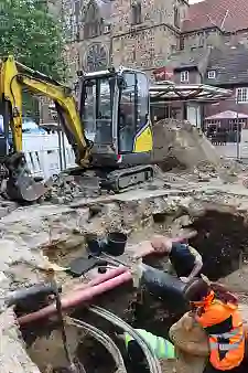 Blick in das tiefe Grabungsloch; gut zu erkennen sind die Rohre und Leitungen, unter denen die archäologischen Funde gemacht wurden. Foto: Landesarchäologie Bremen