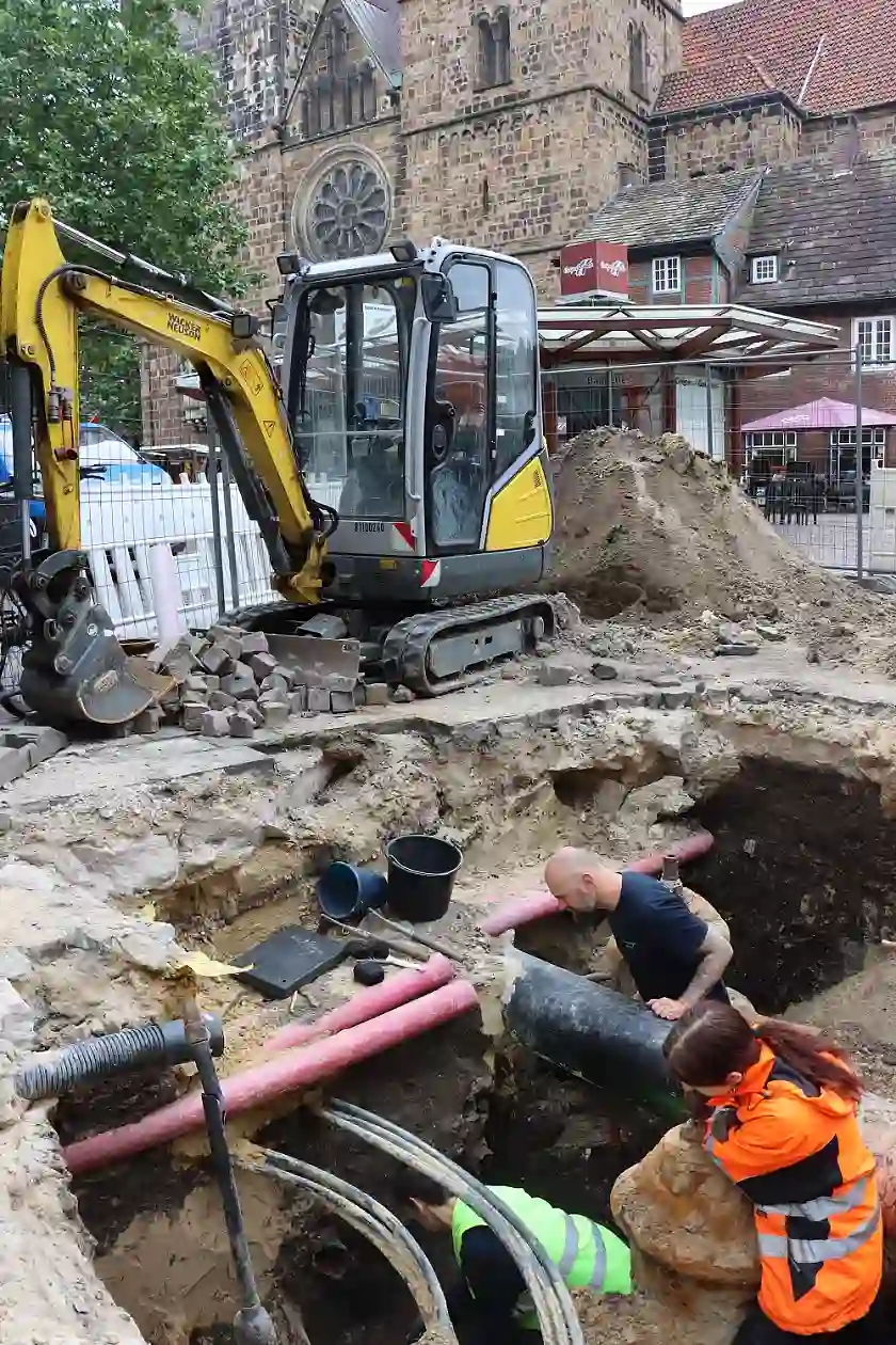 Blick in das tiefe Grabungsloch; gut zu erkennen sind die Rohre und Leitungen, unter denen die archäologischen Funde gemacht wurden. Foto: Landesarchäologie Bremen