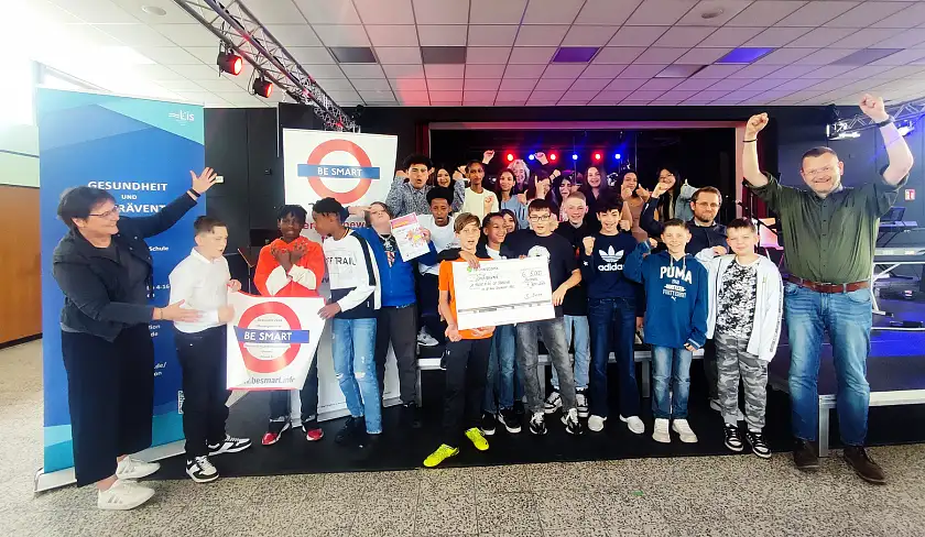 Die Klasse 6b der Oberschule Kurt-Schumacher-Allee hat per Losglück den Hauptpreis des Rauchfrei-Wettbewerbs der Deutschen Krebshilfe erhalten. Dr. Barbara Isensee vom Institut für Therapie- und Gesundheitsforschung (IFT-Nord, links), Birgit Pharao, Vertreterin der AOK Bremen/Bremerhaven (hinten) und Dr. Oliver Peters (Referatsleitung Gesundheit und Suchtprävention, LIS, rechts ) überreichten ihn der Klasse. Foto: Martin Kehl (LIS)