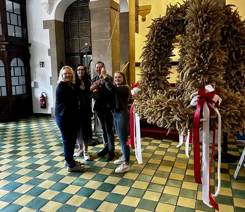 Mit vereinten Kräften wird die Erntekrone der Bremer Landfrauen unter die Decke der Eingangshalle des Rathauses gezogen (von links): Andrea Geerken (1. Vorsitzende der Bremer Landfrauen), Staatsrätin Carmen Emigholz, Hilmer Garbade (Präsident des Bremer Landwirtschaftsverbandes) und Luisa Gartelmann von der Landjugend Bremen-Blockland. Foto: Senatspressestelle