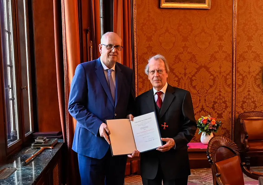 Bürgermeister Andreas Bovenschulte übergibt Prof. Dr. Alfred Rinken die Verleihungsurkunde.