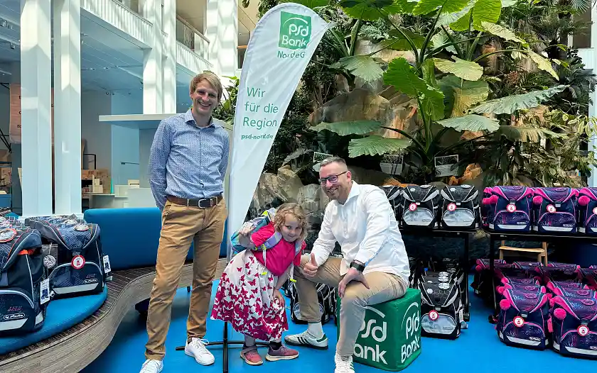 Laura, Besitzerin eines neuen Schulranzens, mit Dominik Schulte, Leiter Omnikanalvertrieb der PSD Bank Nord (r.) und Referatsleiter Dr. Sören Hoyer im Überseemuseum. 