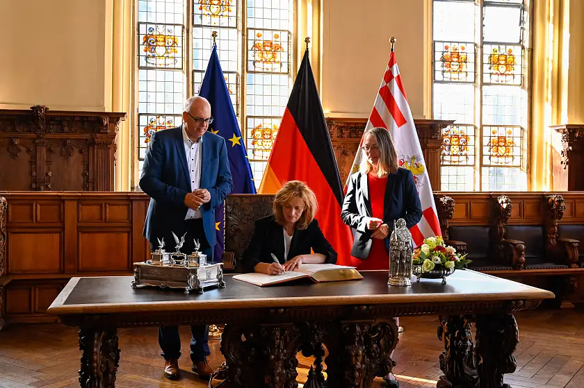 Bundesbildungsministerin Karin Prien (Mitte) trägt sich im Beisein von Bürgermeister Andreas Bovenschulte und der Senatorin für Kinder und Bildung, Sascha Karolin Aulepp in das Goldene Buch ein. 