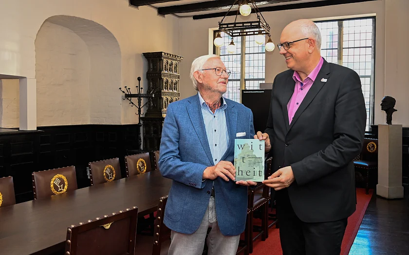 Prof. Gerold Wefer (links) übergibt Bürgermeister Andreas Bovenschulte in der Wittheitsstube des Rathauses die Dokumentation zum 100-jährigen Bestehen der Wittheit zu Bremen. 