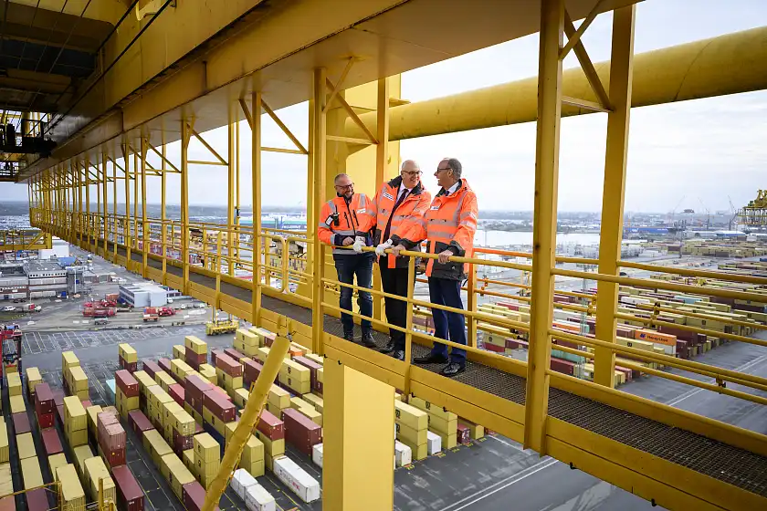 Bundeskanzler Friedrich Merz, Bürgermeister Andreas Bovenschulte lassen sich von Marc Dieterich (Managing Director Eurogate Container Terminal Bremerhaven) von einer Containerbrücke aus den Hafen erläutern (v.r.n.l.).