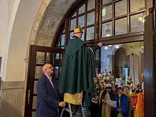 Der Bürgermeister hält die Leiter, der Sternsinger schreibt:  20*C+M+B+26 steht seit heute über dem Eingang zum Rathaus. 