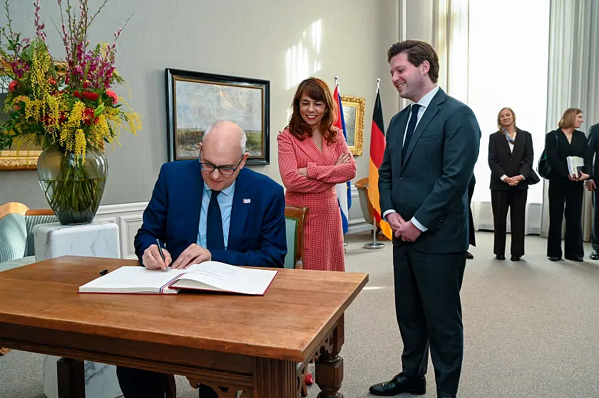 Bürgermeister Andreas Bovenschulte trägt sich im Beisein von Mei Li Vos, Vorsitzende der Ersten Kammer, und Thom van Campen, Vorsitzender der Zweiten Kammer, in das Gästebuch der Generalstaaten ein. 