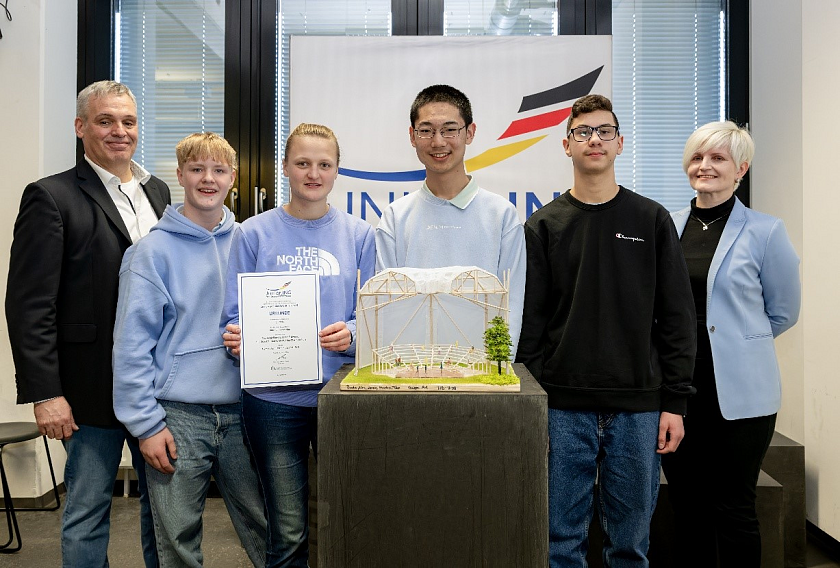 Über den 1. Preis in der Alterskategorie Klasse 9-13 mit dem Arenadach-Modell Roof of Innovation freuen sich Line Marit Wolters, Paula Scholze, Lasse Erdwien, Teo Angjelkovski und Marko Shen aus der 9. Klasse des Gymnasiums Horn gemeinsam mit den Vorstandsmitgliedern der Ingenieurkammer Bremen Jens Behnke und Linda Petrick. 