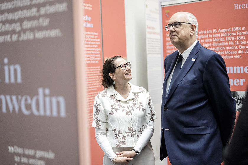 Die Direktorin des Deutschen Auswandererhauses, Simone Blaschka, erläutert Bürgermeister Andras Bovenschulte die Ausstellung im Foyer des Bundesrats. 