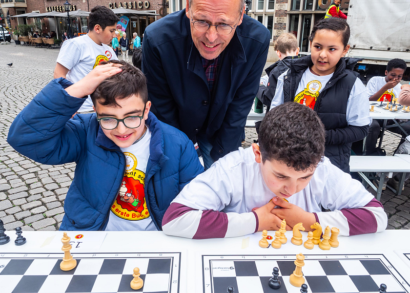 Joud (links) und Hidir von der Grundschule an der Landskronastraße haben zusammen mit fast 1.200 weiteren Kindern an Bremens größtem Schachturnier teilgenommen. Senator Mark Rackles schaute den Kindern auf dem Marktplatz dabei über die Schulter.  