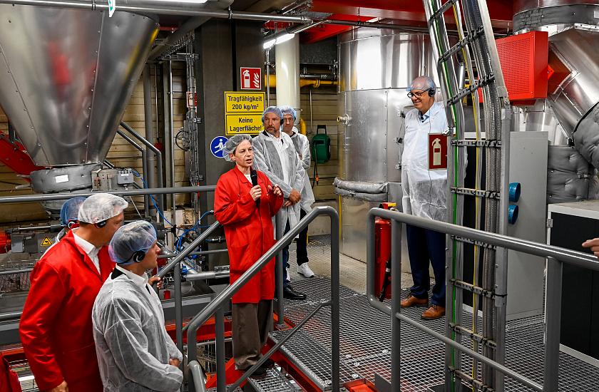 Bürgermeister Anderas Bovenschulte (rechts in der Fertigung von Melitta. Werksleiterin Dörte Lämmerhirt (mit Mikrofon) erläutert die Produktion. 