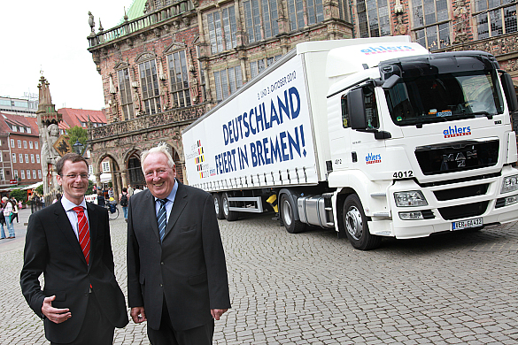 Senator Martin Günthner und Inhaber Bernhard Henzel präsentieren auf dem Bremer Marktplatz einen der sympathischen Werbeträger für den Tag der Deutschen Einheit