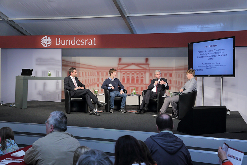 Jens Böhrnsen diskutiert mit den beiden Schülern Jonas Oldenburg (re.) und Fabian Weindel sowie dem Moderator Matthias Killing (li.) im Zelt des Bundesrats u.a. über die Finanzbeziehungen zwischen dem Bund und den Ländern