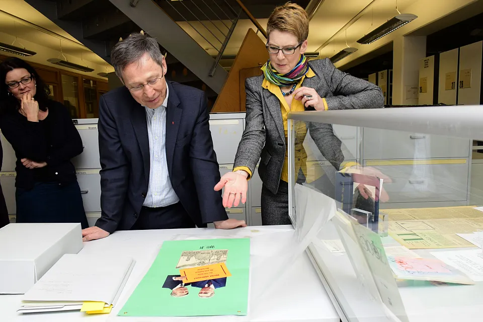 Der B&uuml;rgermeister betrachtet eine Collage des tschechoslowakischen Dissidenten und Aktionsk&uuml;nstlers Karel Trinkewitz, der mit seinem Spott nicht nur die Parteichefs der Ostblockl&auml;nder &uuml;berzog, sondern auch vor westlichen Staatschefs nicht haltmachte. Auf der Collage sieht man Helmut Schmidt im vertrauten Umgang mit dem sowjetischen Parteichef Leonid Breschnew, unter ihnen eine Karikatur des polnischen Generalsekret&auml;rs Jaruzelski, der 1981 das Kriegsrecht in Polen ausrief. Dazwischen prangt ein Aufkleber, wie er f&uuml;r Umzugskartons benutzt wird, auf dem vieldeutig steht: "Nicht st&uuml;rzen"